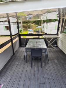 un patio con mesa y sillas en una terraza en Mobil-home 6 personnes climatisé le Miami en Saint-Chéron