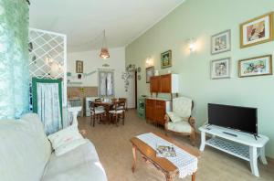 un soggiorno con divano bianco e TV di Casa Provence Family & Friends Mare & Natura ad Alghero
