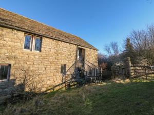 an old brick building with a staircase next to a fence at Wyndell Cruck Cottage in Sheffield