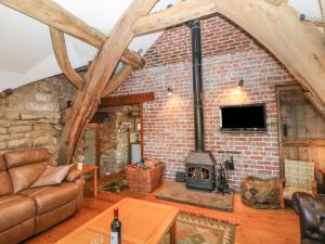 a living room with a brick wall and a fireplace at Wyndell Cruck Cottage in Sheffield