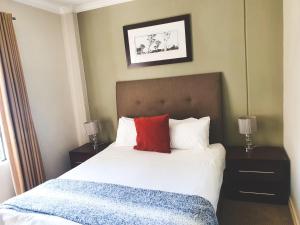 a bedroom with a large bed with a red pillow at Westpoint Sandton Apartments in Johannesburg