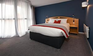 a bedroom with a large bed and a blue wall at Holiday Inn Express Liverpool-Albert Dock, an IHG Hotel in Liverpool
