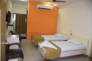 a hotel room with two beds and a tv at Hotel Uma Executive Lodging in Nānded