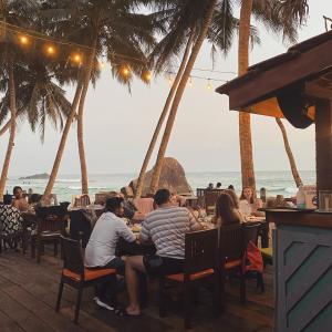a group of people sitting at a restaurant on the beach at Sri Gemunu Beach Resort in Unawatuna