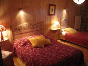 a bedroom with two beds in a room with wooden walls at Le Francillon in Les Estables