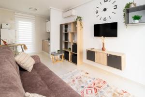 a living room with a couch and a clock on the wall at Espanatour AZAHAR DEL MAR in Torrevieja
