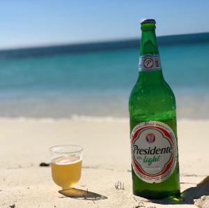 a bottle of beer and a glass on the beach at Villa Elegante y Familiar en Pedernales, Cerca de la Playa del pueblo, Residencial SFA in Pedernales