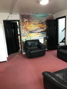 a living room with black leather chairs and a painting at Finn McCools Giants Causeway Hostel in Bushmills