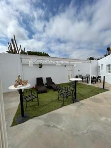 eine Terrasse mit 2 Tischen, Stühlen und Gras in der Unterkunft Apartamentos Elena in Lajares