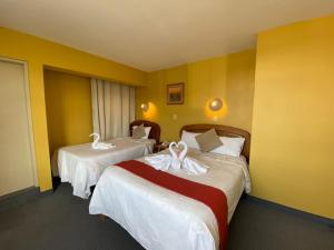 two beds in a hotel room with yellow walls at Hostal Oscar Inn in Puno