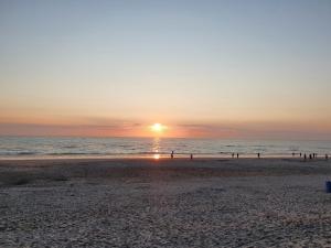 um pôr do sol na praia com pessoas caminhando na praia em Casa Allegria - Zuiderbosch em Bergen