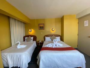 Dos camas en una habitación de hotel con cisnes. en Hostal Oscar Inn, en Puno
