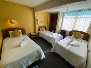 a hotel room with two beds and a window at Hostal Oscar Inn in Puno