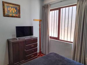 ein Schlafzimmer mit einem Bett und einem TV auf einer Kommode in der Unterkunft Depto Grande con terraza, la mejor ubicación in Tarija