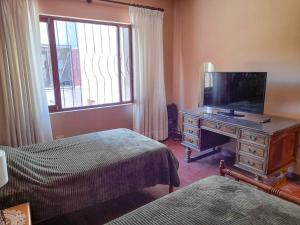 1 Schlafzimmer mit 2 Betten und einem Schreibtisch mit einem TV in der Unterkunft Depto Grande con terraza, la mejor ubicación in Tarija