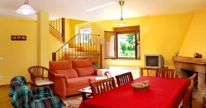 sala de estar con mesa roja y sofá en Casa Rural Las Verdes l y II, en Torre de Babia