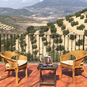 two chairs and a table on a patio with a view at Cortijo Rocas Altas in Iznájar