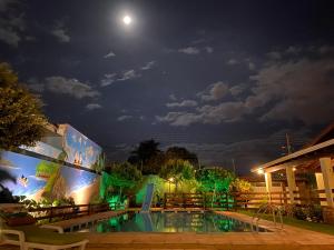 a pool at night with the moon in the background at Pousada Vale do Rubi in Londrina
