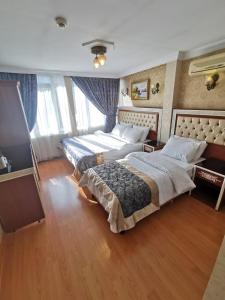 2 łóżka w pokoju hotelowym z drewnianą podłogą w obiekcie Big Apple Hotel w Stambule