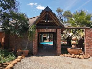 a brick entrance to a resort with a swimming pool at Boskoppie Lion & Tiger Reserve in Kroonstad