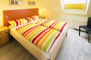 ノルトダイヒにあるFerienwohnung Likedeelersのベッドルーム1室(カラフルな毛布付きのベッド1台付)
