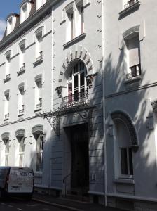 a white building with a door and a balcony at Hôtel 19'Cent in Le Creusot