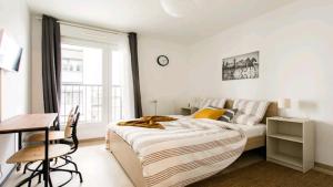 a bedroom with a bed and a desk and a window at Luxury Apartment near Paris la Défense with secured Parking in Bois-Colombes