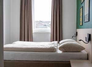 Bett in einem Schlafzimmer mit Fenster in der Unterkunft SLEEEP HOTEL Ansfelden in Linz