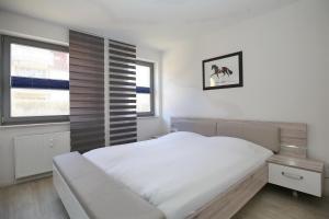ein weißes Schlafzimmer mit einem Bett und einem Fenster in der Unterkunft Hanse-Haus Wohnung 04 in Boltenhagen