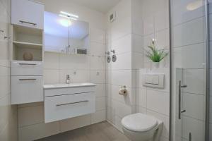 ein weißes Badezimmer mit Toilette und Waschbecken in der Unterkunft Hanse-Haus Wohnung 04 in Boltenhagen