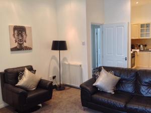 a living room with two leather couches and a lamp at Mode Apartments in Aberdeen