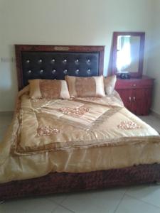 - une chambre avec un grand lit et une tête de lit en bois dans l'établissement Hotel Ain Leuh, à Aïn Leuh