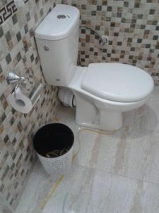 a bathroom with a white toilet and a bucket at Hotel Ain Leuh in Aïn Leuh