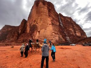 a group of people riding camels in the desert at Wadi Rum Quiet Village Camp in Wadi Rum