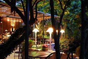 une terrasse avec des lumières, une table et des chaises dans l'établissement Hostellerie Le Paradou, à Lourmarin