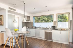 a kitchen with white cabinets and a table with chairs at Blue Port in Mahón