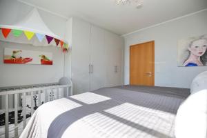 - une chambre blanche avec un lit et une porte en bois dans l'établissement Villa Bernstein Wohnung 06, à Boltenhagen
