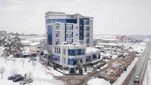 um grande edifício com neve no chão ao lado de uma rua em Hotel Ženeva Lux em Kragujevac