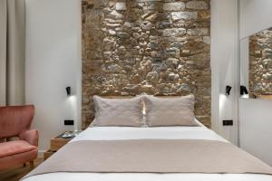1 dormitorio con 1 cama grande y pared de piedra en J&A Luxury Residence, en Atenas