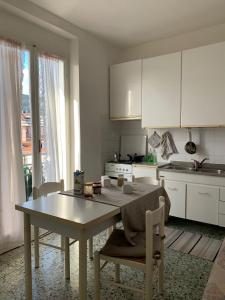 Fiumaretta di AmegliaAppartamento 8的一间带桌椅的厨房和一间带白色橱柜的厨房