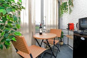 een tafel en stoelen met een fles wijn op een balkon bij The Creteil Shelter - Duke Housing in Créteil