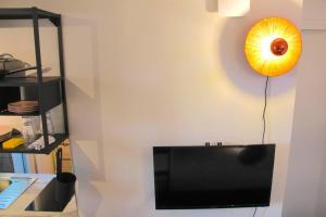 een flatscreen-tv zittend op een muur met een klok bij The Creteil Shelter - Duke Housing in Créteil