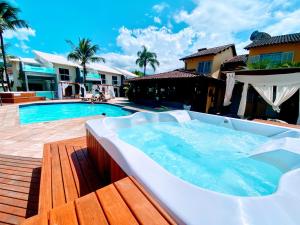 Pousada Villa del Sol في باراتي: جلسة حوض استحمام ساخن كبير بجانب مسبح