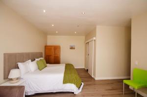 Small Bay Guest House في بلوبيرجستراند: غرفة نوم بسرير كبير وكرسي أخضر