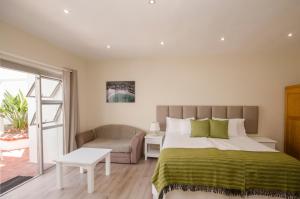 a bedroom with a bed and a couch and a chair at Small Bay Guest House in Bloubergstrand