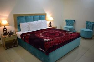 a bedroom with a large bed and two blue chairs at Royal Castle in Rahimyar Khan