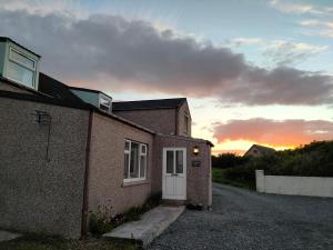 a building with a white door and a sunset in the background at Stromness Apartments in Stromness