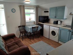 a living room with a couch and a table and a kitchen at Stromness Apartments in Stromness