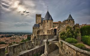 um velho castelo com uma escada em frente a uma cidade em ** Au Canal du Midi - JACCUZZI & luxueux appartements ** em Carcassonne