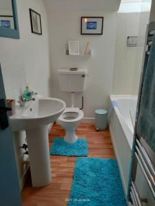 łazienka z umywalką, toaletą i wanną w obiekcie Stromness Apartments w mieście Stromness